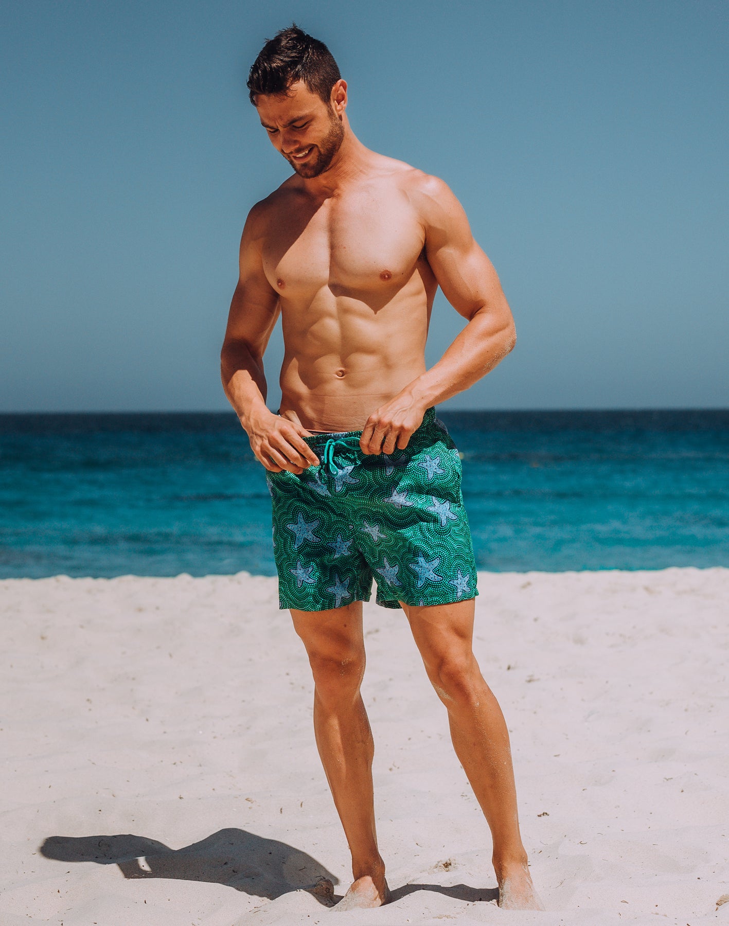 Sustainable Men's Star Fish Print Shorts from SevenC's - Front View on model at beach