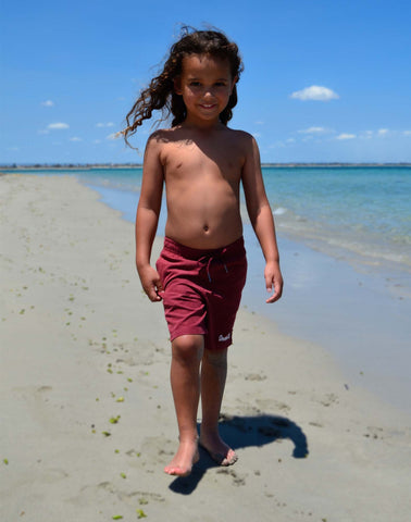 SevenC's Kids' Recycled Polyester Shorts in Burgundy Model on beach
