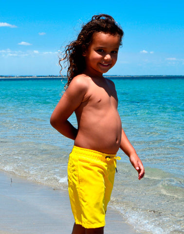 SevenC's Kids' Recycled Polyester Shorts in Yellow - Side View on model at beach